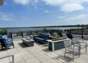 Thumbnail 17 of 55 - a rooftop patio with chairs and tables and a river in the background