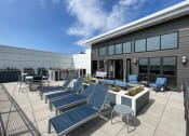 Thumbnail 15 of 55 - a patio with blue lounge chairs and tables outside of a building