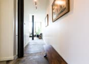 Thumbnail 9 of 9 - A hallway with a wooden bench and a painting on the wall.