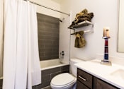 Thumbnail 5 of 9 - A bathroom with a white toilet, a white shower curtain, and a white sink.