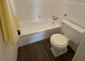 Thumbnail 7 of 18 - A small bathroom with a toilet, tub, and window.