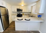 Thumbnail 1 of 18 - A kitchen with a refrigerator, microwave, oven, and sink.
