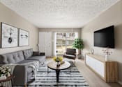 Thumbnail 7 of 10 - A living room with a grey couch, a coffee table, a chair, a plant, and a flat screen TV mounted on the wall.