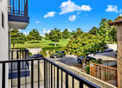 Thumbnail 12 of 14 - A balcony overlooks a parking lot and green trees.