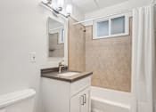 Thumbnail 27 of 35 - A bathroom with a white tub, sink, and shower.