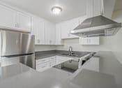 Thumbnail 7 of 35 - A modern kitchen with a stainless steel refrigerator and a range hood.