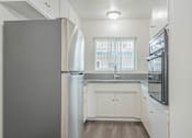 Thumbnail 8 of 35 - A kitchen with white cabinets and a grey refrigerator.