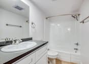 Thumbnail 21 of 24 - A white bathroom with a sink, toilet, and shower.