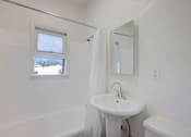 Thumbnail 28 of 40 - A white bathroom with a sink, mirror, and tub.