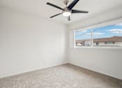 Thumbnail 23 of 35 - A room with a ceiling fan and carpeted floor.