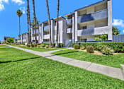 Thumbnail 3 of 23 - A row of modern apartment buildings with green lawns in front.