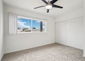 Thumbnail 22 of 35 - A room with a ceiling fan and a window overlooking a residential area.