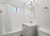 Thumbnail 28 of 35 - A white bathroom with a sink, mirror, and tub.
