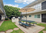 Thumbnail 29 of 35 - A patio with a table and chairs under an umbrella.