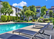 Thumbnail 6 of 23 - A pool surrounded by trees and bushes with sun loungers.