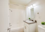 Thumbnail 18 of 20 - A white bathroom with a sink, mirror, and bathtub.