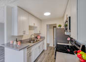 Thumbnail 8 of 18 - A modern kitchen with white cabinets and a stainless steel stove.