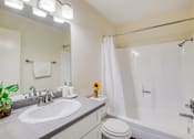 Thumbnail 15 of 18 - A bathroom with a white toilet, sink, and shower.