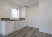 Thumbnail 7 of 16 - A kitchen with white cabinets and a window.