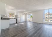 Thumbnail 9 of 16 - A spacious living room with a kitchen area and hardwood flooring.