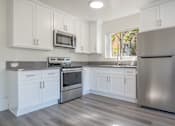 Thumbnail 5 of 16 - A kitchen with white cabinets and a stainless steel refrigerator.