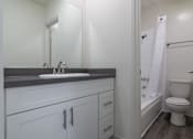 Thumbnail 15 of 16 - A white bathroom with a sink, toilet, and bathtub.