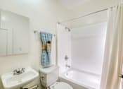 Thumbnail 11 of 12 - A white bathroom with a sink, toilet, and bathtub.