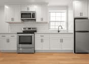 Thumbnail 4 of 14 - A modern kitchen with white cabinets and stainless steel appliances.