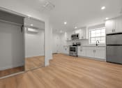 Thumbnail 5 of 14 - A kitchen with wooden floors and white walls.