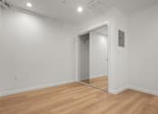 Thumbnail 8 of 14 - A room with a wooden floor and a mirror on the wall.