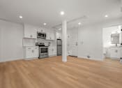 Thumbnail 6 of 14 - A kitchen with white cabinets and a wooden floor.