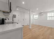 Thumbnail 7 of 14 - A kitchen with white countertops and wooden floors.