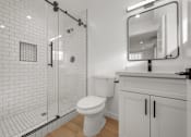 Thumbnail 10 of 14 - A white toilet in a bathroom with a white tiled shower.