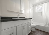 Thumbnail 19 of 19 - A white bathroom with a sink, toilet, and bathtub.