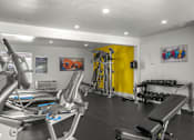 Thumbnail 59 of 64 - A gym with a rowing machine, a bench press, and a yellow wall at Sunset Square, West Covina, 91790