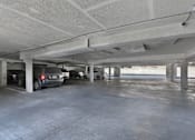 Thumbnail 13 of 14 - A parking garage with a few cars parked.
