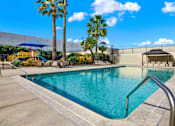 Thumbnail 48 of 55 - A swimming pool surrounded by palm trees and a blue umbrella.