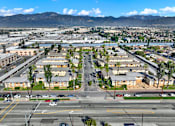 Thumbnail 55 of 55 - A large, open parking lot is surrounded by buildings and palm trees.