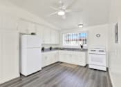 Thumbnail 15 of 55 - A white kitchen with a refrigerator, oven, and a ceiling fan.