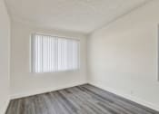 Thumbnail 28 of 55 - A room with a window covered by white blinds and wooden flooring.