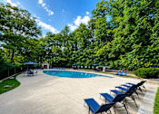 Thumbnail 3 of 21 - A pool surrounded by trees and chairs.