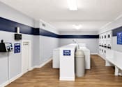 Thumbnail 14 of 21 - A room with a white and blue color scheme has a white sink and a white trash can.