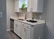 Thumbnail 6 of 28 - A kitchen with white cabinets and a black countertop.