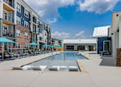 Thumbnail 20 of 45 - a swimming pool with lounge chairs and umbrellas in front of an apartment building in Asheville NC