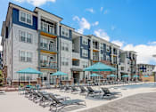 Thumbnail 31 of 45 - an outdoor swimming pool with chaise lounge chairs and umbrellas in front of an apartment in Asheville NC