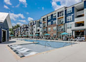 Thumbnail 4 of 45 - a swimming pool with umbrellas in front of an apartment building in Asheville