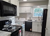 Thumbnail 1 of 28 - A black stove top oven with a white stove top and a black microwave above it.