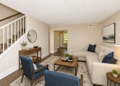 Thumbnail 7 of 21 - A living room with a white couch, blue chairs, and a wooden coffee table.