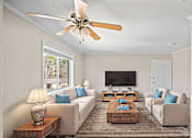 Thumbnail 6 of 10 - A living room with a white couch, a wooden coffee table, and a ceiling fan.