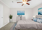 Thumbnail 8 of 10 - A bedroom with a bed, a ceiling fan, and a painting of a beach scene on the wall.